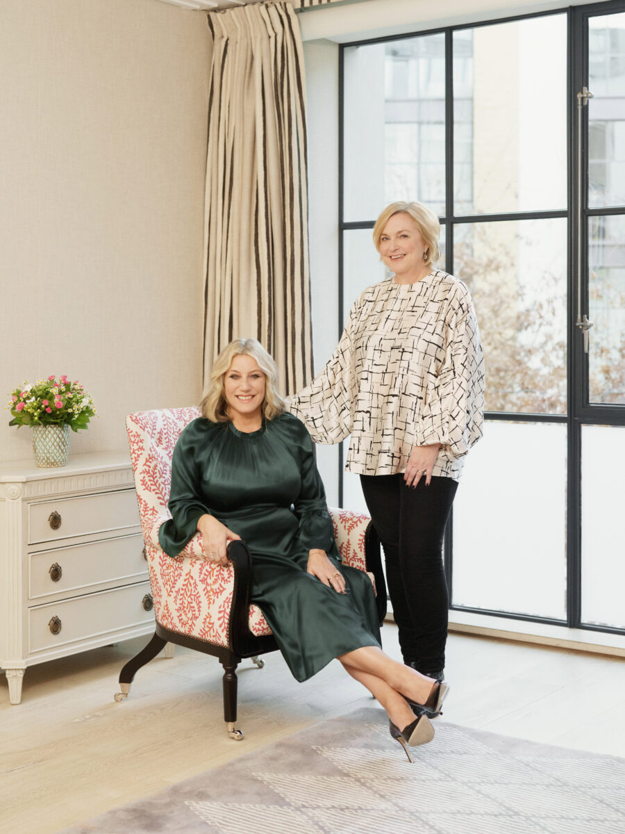 M&C Saatchi Talk Jane Boardman pictured standing in white shirt with Millie Kendall who is sat on a chair in a green dress. Boardman has been awarded an OBE for services to beauty and fashion.