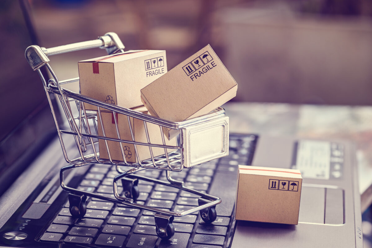 Image of trolley with boxes on computer keyboard, depicting online shopping. Over half (57%) of CPG (consumer packaged goods) marketers see e-commerce as a top priority, highlighting the role of online shopping across the industry.