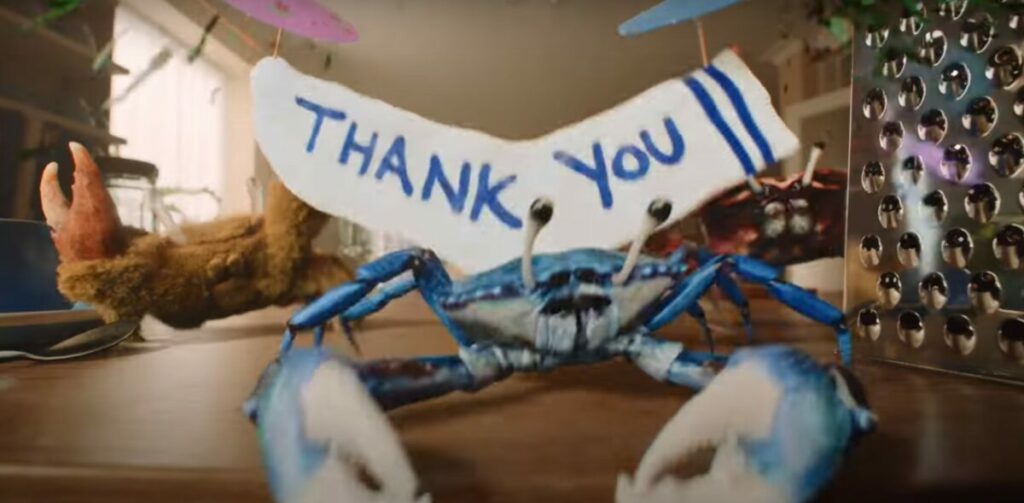 A singing crab stands on a kitchen counter in front of a sign which reads "Thank you". OceanSaver features Bristolian sea shanty group The Longest Johns in its TV debut campaign encouraging people to switch to more environmentally friendly laundry products. 