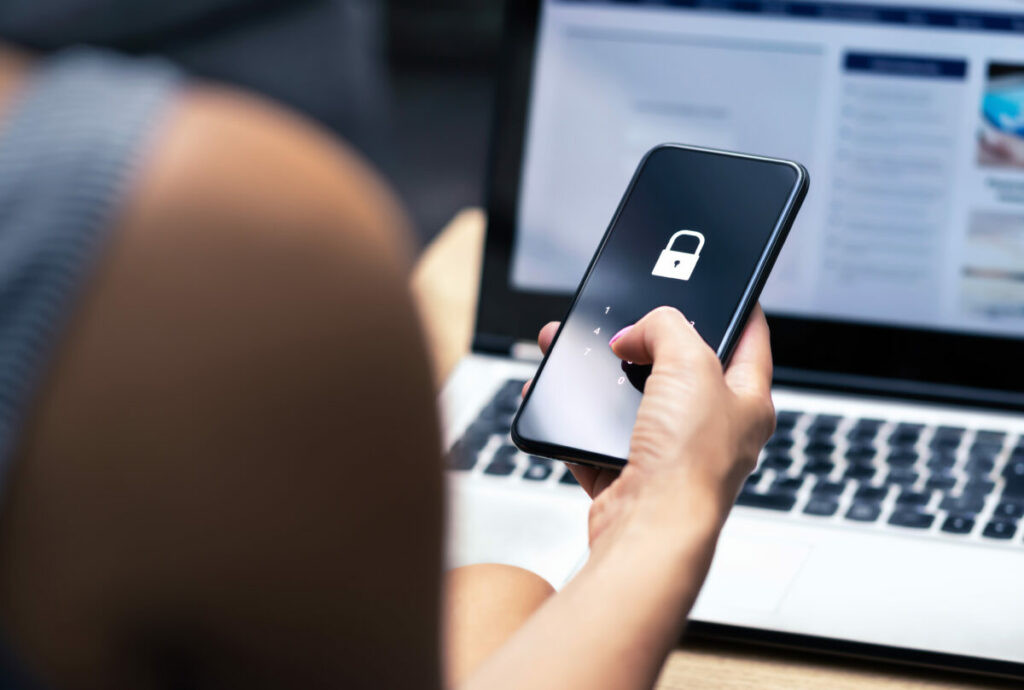 A person scrolls on their phone at their desk and is met with a lock symbol indicating privacy. The Data & Marketing Association (DMA) is calling on the next government to put AI at the centre of its growth and innovation strategies