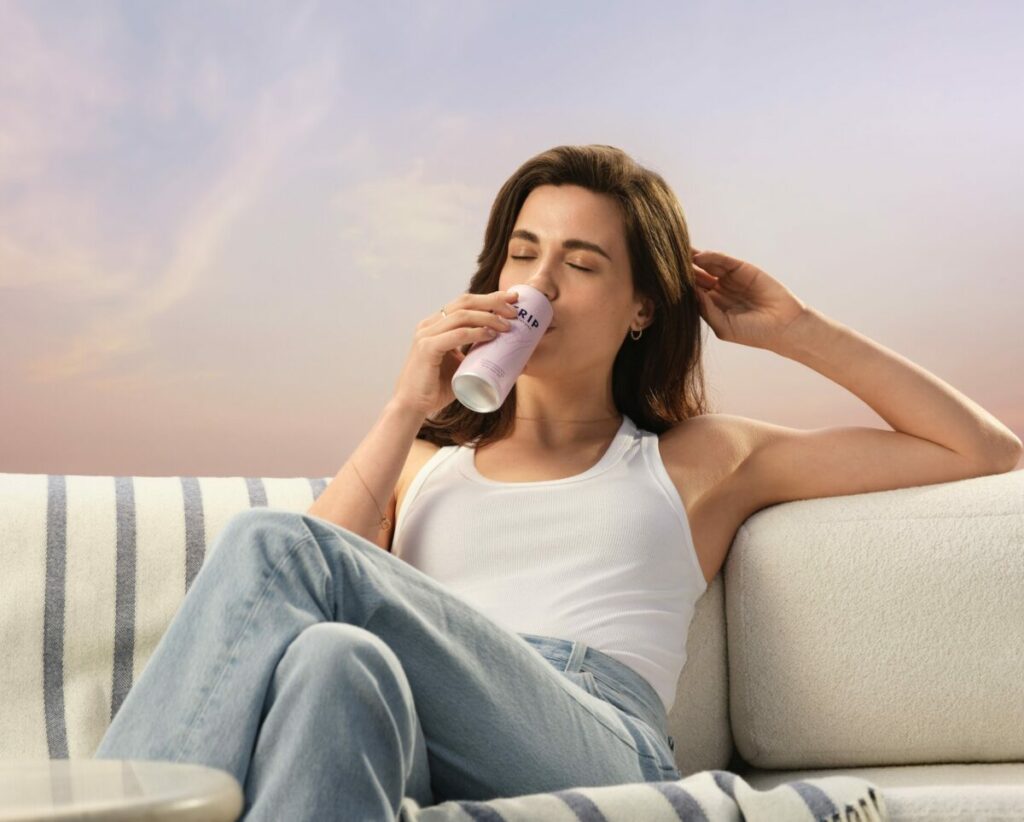 A woman lounges back on a stylish looking sofa in comfortable bagging jeans in calming surroundings, she is sipping on a Trip CBD drink. Trip has launched its first ever £multi-million ad campaign in an effort to showcase how the CBD-infused drink can help viewers find their calm.