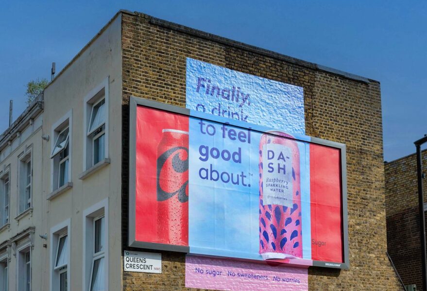 A dash billboard reading finally a drink to feel good about with the text @No sugar, No Sweeteners, Now worries above a red looking billboard.Part of the anti artificial sweetener spot from Dash looks suspiciously like *that* enormous fizzy drinks firm.