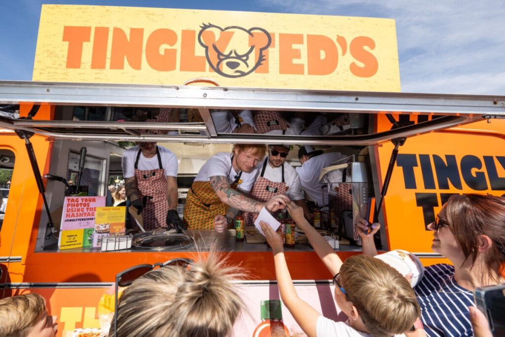 Ed Sheeran in an orange Tingly Ted's van outside Sainsbury's London Colney. Grammy-winning artist Ed Sheeran surprised shoppers at Sainsbury's London Colney by switching a pen for sauce and handing over the first "sauceographs